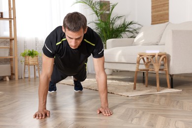 Photo of Handsome man doing high plank exercise on floor at home