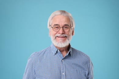Photo of Portrait of stylish grandpa with glasses on light blue background