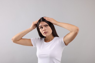 Photo of Emotional woman examining her hair and scalp on grey background