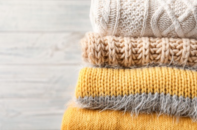 Photo of Stack of warm knitted clothes on light background