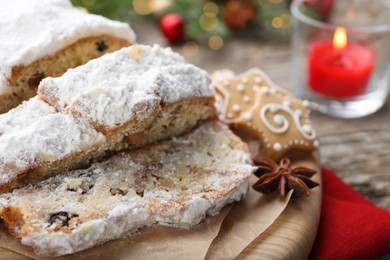 Photo of Traditional Christmas Stollen with icing sugar on wooden table, closeup