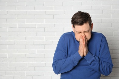 Photo of Mature man suffering from cold near brick wall. Space for text