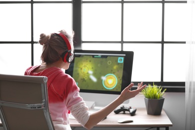 Photo of Young woman playing video game at home