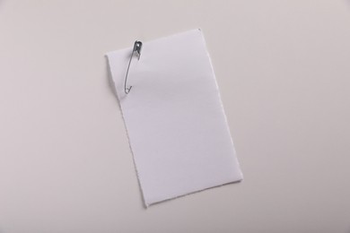 Photo of Sheet of paper attached with safety pin on white background, top view