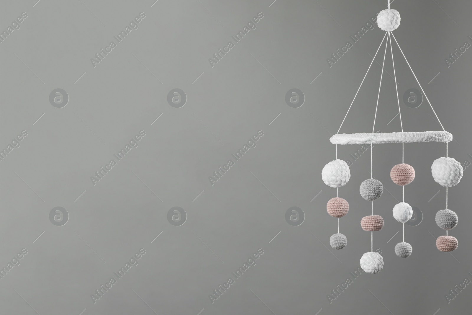 Photo of Cute baby crib mobile on grey background. Space for text