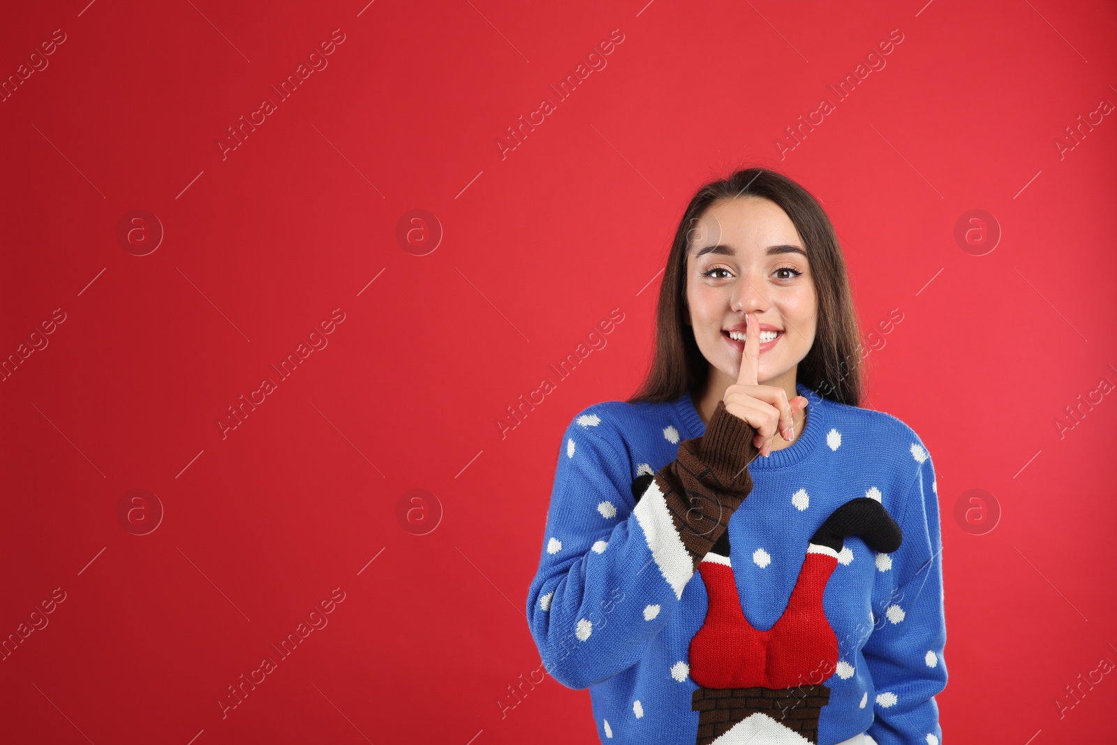 Photo of Young woman in Christmas sweater on red background, space for text