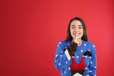 Young woman in Christmas sweater on red background, space for text