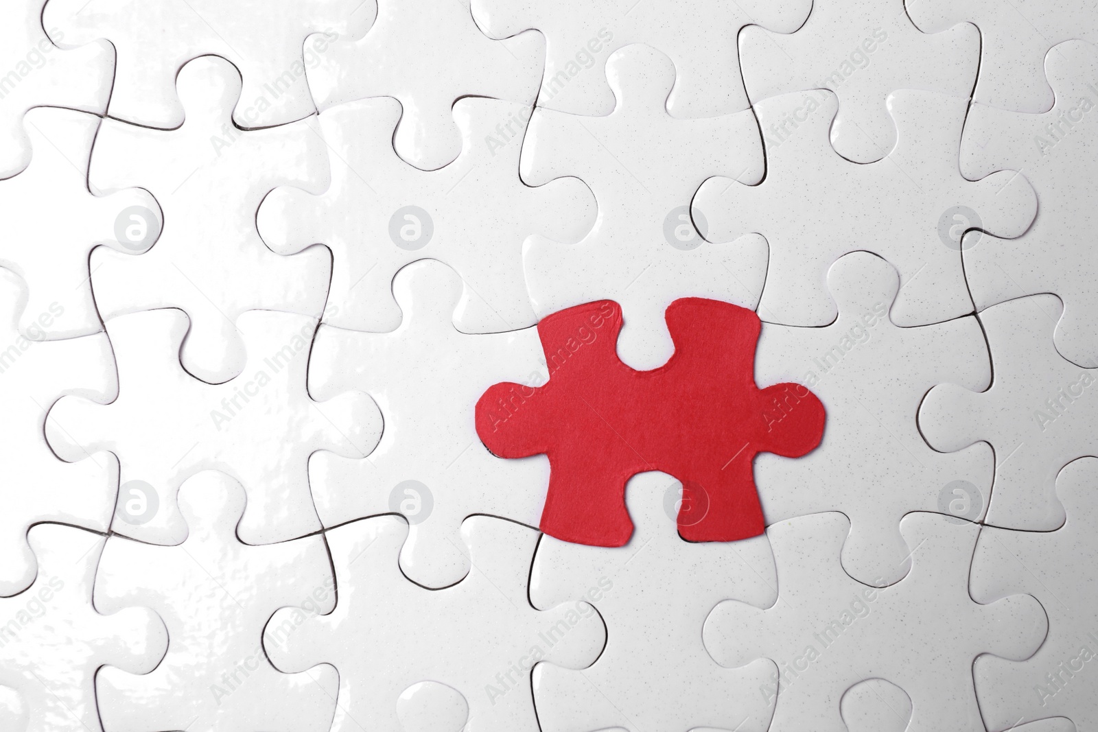 Photo of White jigsaw puzzles and red one as background, top view