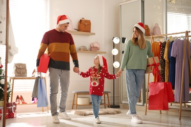 Photo of Happy family with Santa hats doing Christmas shopping in store