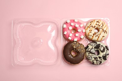 Photo of Box of delicious donuts on pink background, top view