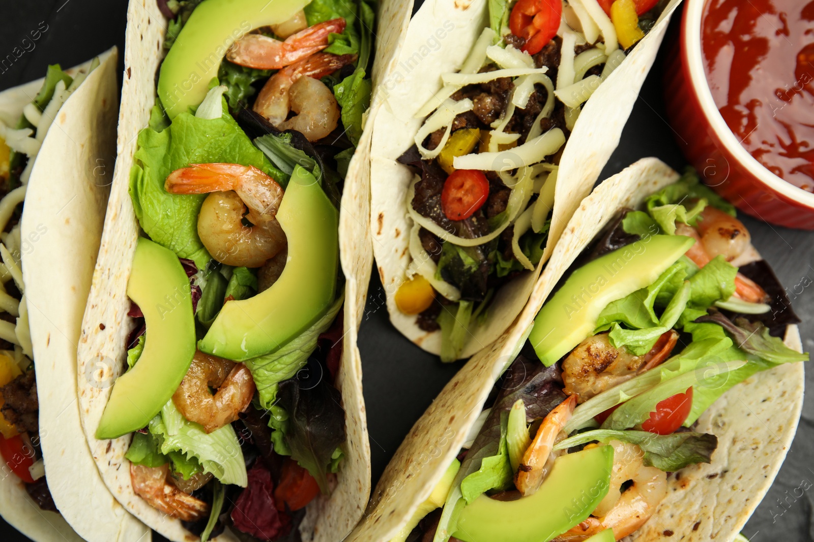 Photo of Delicious tacos and sauce on black table, flat lay