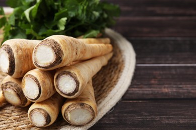 Photo of Raw parsley roots and fresh herb on wooden table, closeup. Space for text