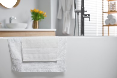 Photo of Fresh white towels on tub in bathroom. Space for text