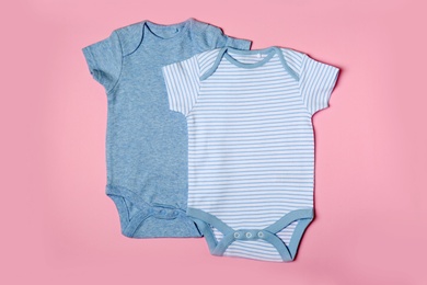 Photo of Cute baby onesies on color background, top view