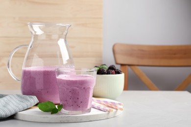Photo of Delicious blackberry smoothie and mint on white table indoors, space for text