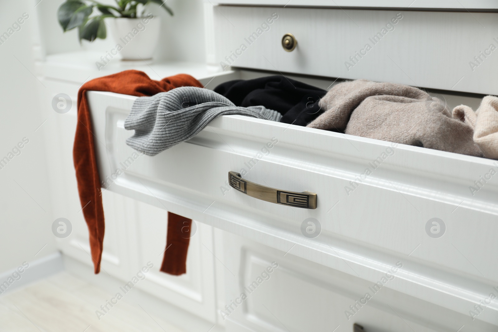 Photo of Cluttered chest of drawers indoors, closeup. Clothes in mess