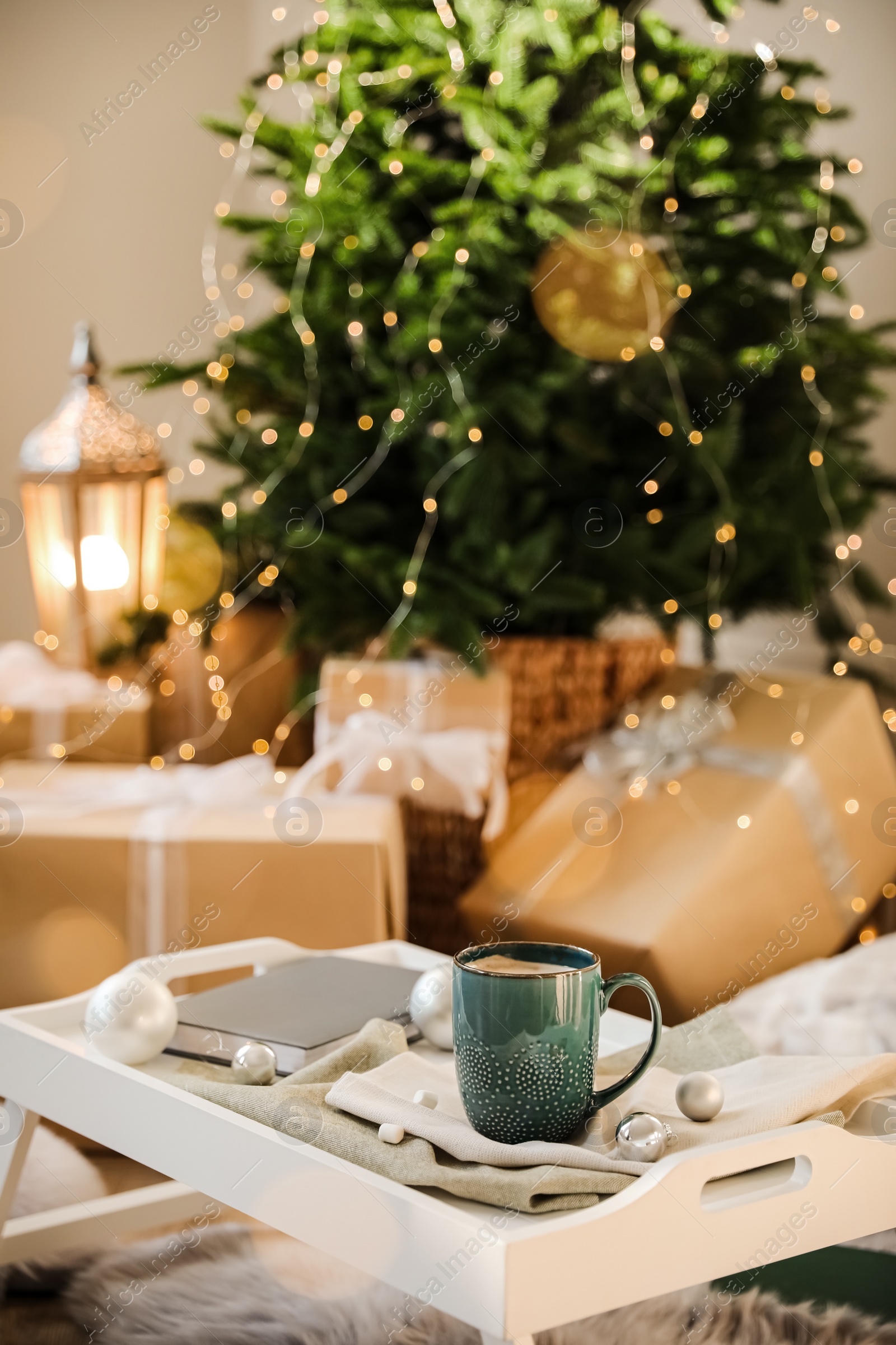 Photo of Cup of cocoa, book and balls on tray at home. Christmas celebration