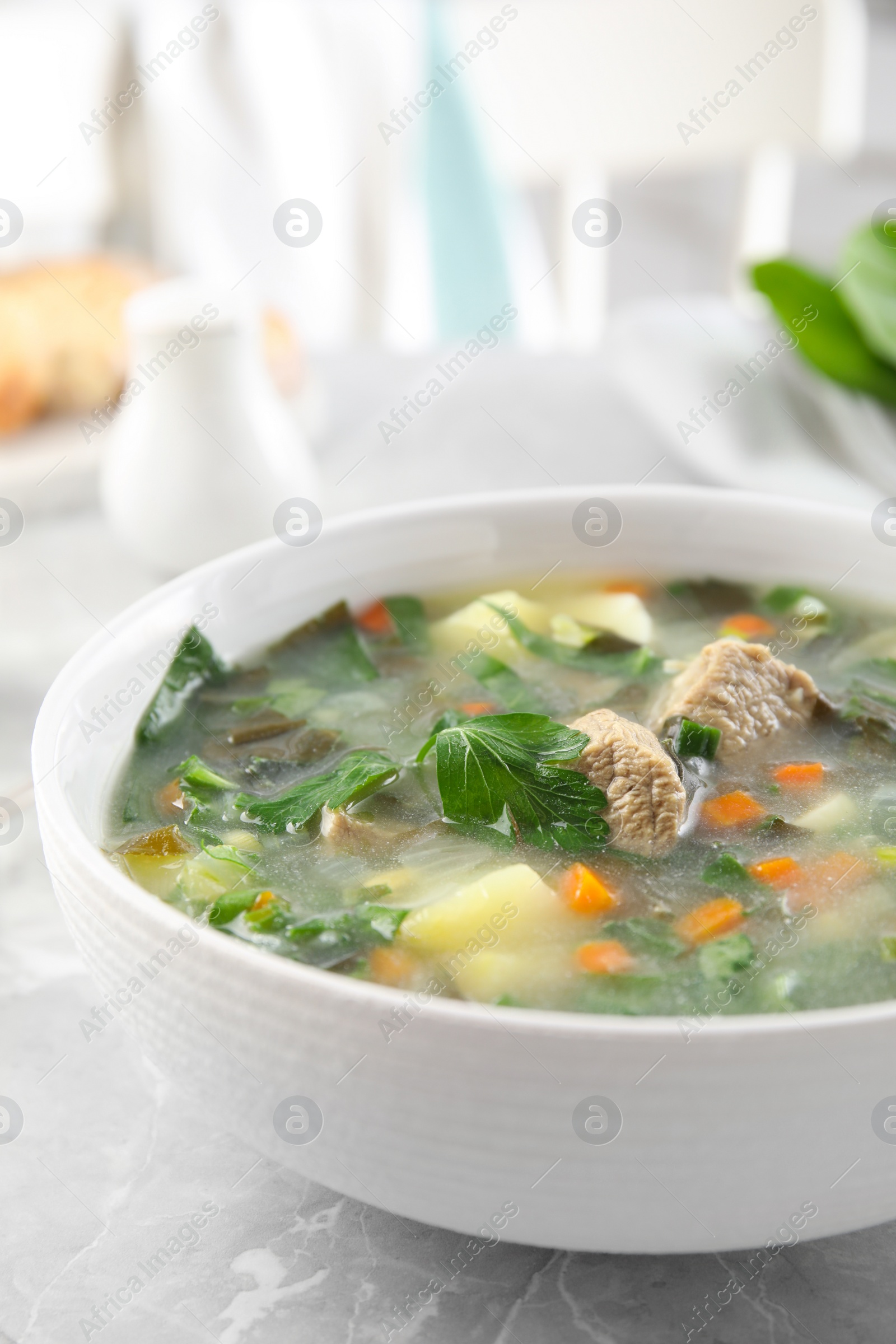 Photo of Delicious sorrel soup with meat served on marble table, closeup