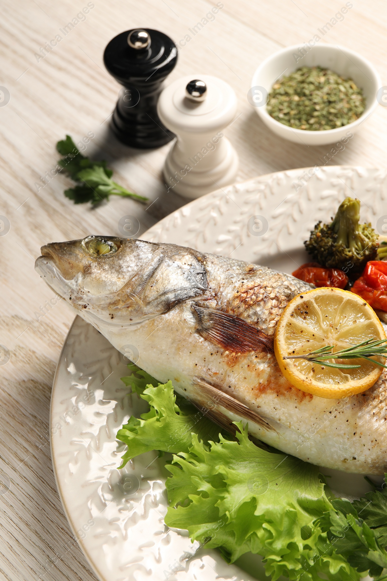 Photo of Delicious baked fish and vegetables on wooden table