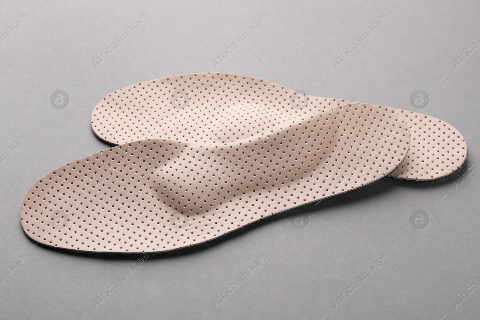 Photo of Beige orthopedic insoles on light grey background, closeup