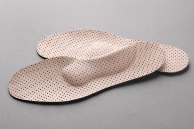 Photo of Beige orthopedic insoles on light grey background, closeup