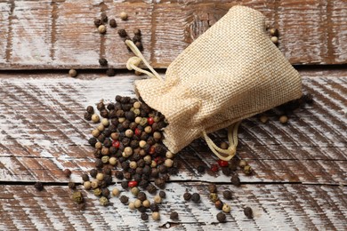 Photo of Aromatic spice. Different peppers in burlap bag on wooden table, top view