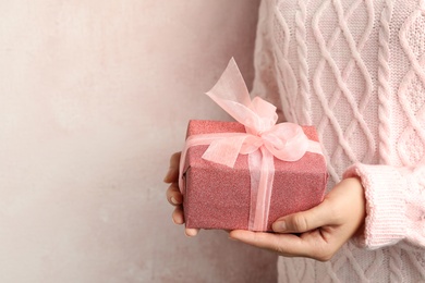 Woman holding beautiful Christmas gift on light background, closeup