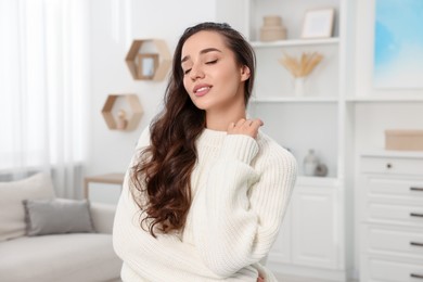 Photo of Beautiful young woman in stylish warm sweater at home
