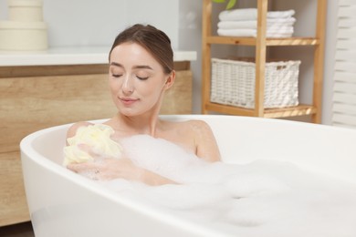 Photo of Woman taking bath with shower gel in bathroom