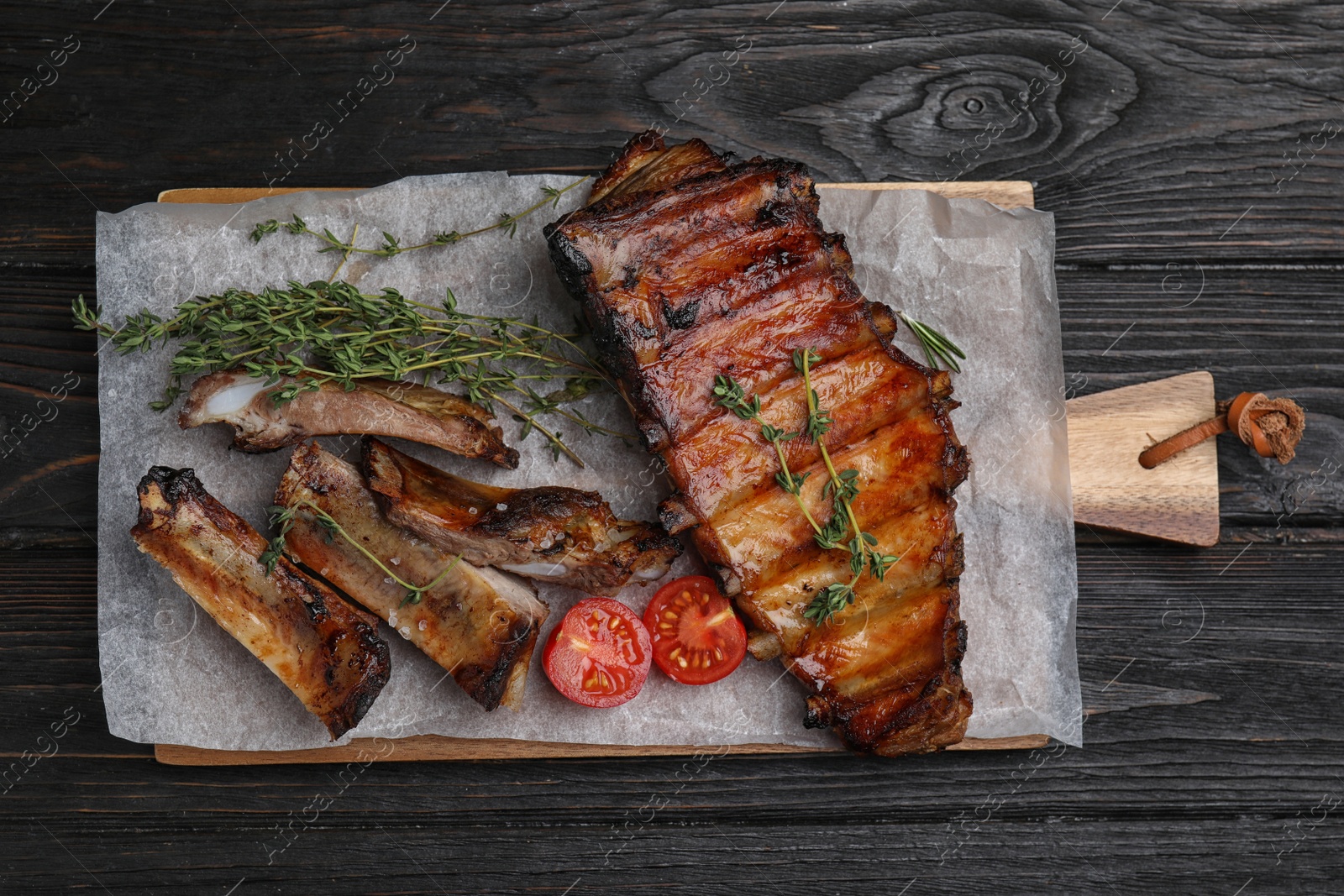 Photo of Tasty grilled ribs on black wooden table, flat lay