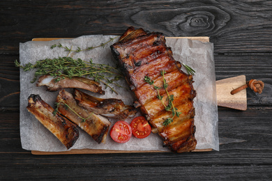 Photo of Tasty grilled ribs on black wooden table, flat lay