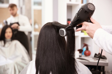 Photo of Professional male hairdresser working with client in salon