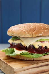 Photo of Tasty homemade cheeseburger with lettuce on wooden board, closeup