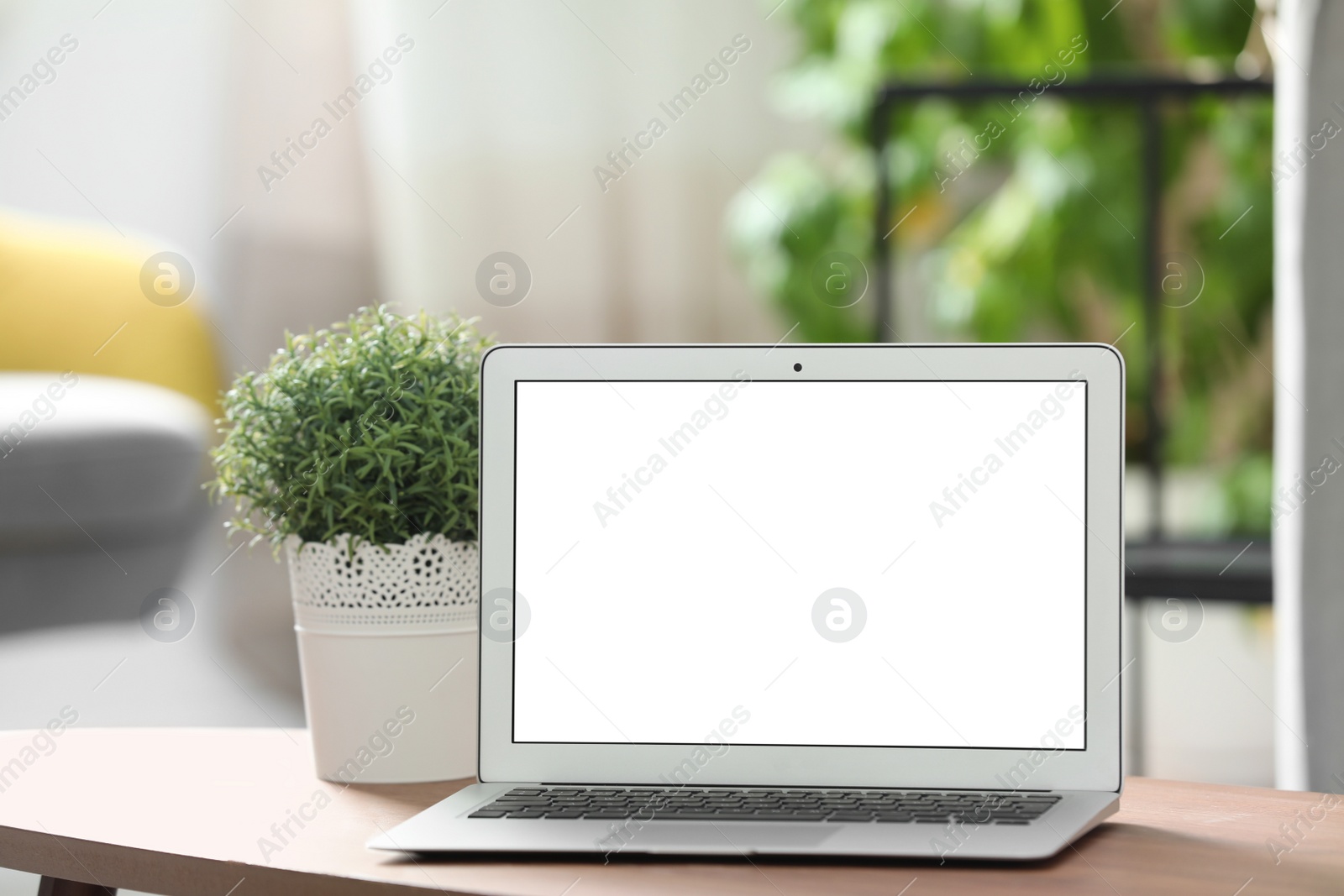 Photo of Laptop with blank screen on table indoors. Space for text