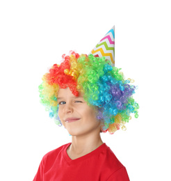 Photo of Little boy in clown wig and party hat on white background. April fool's day