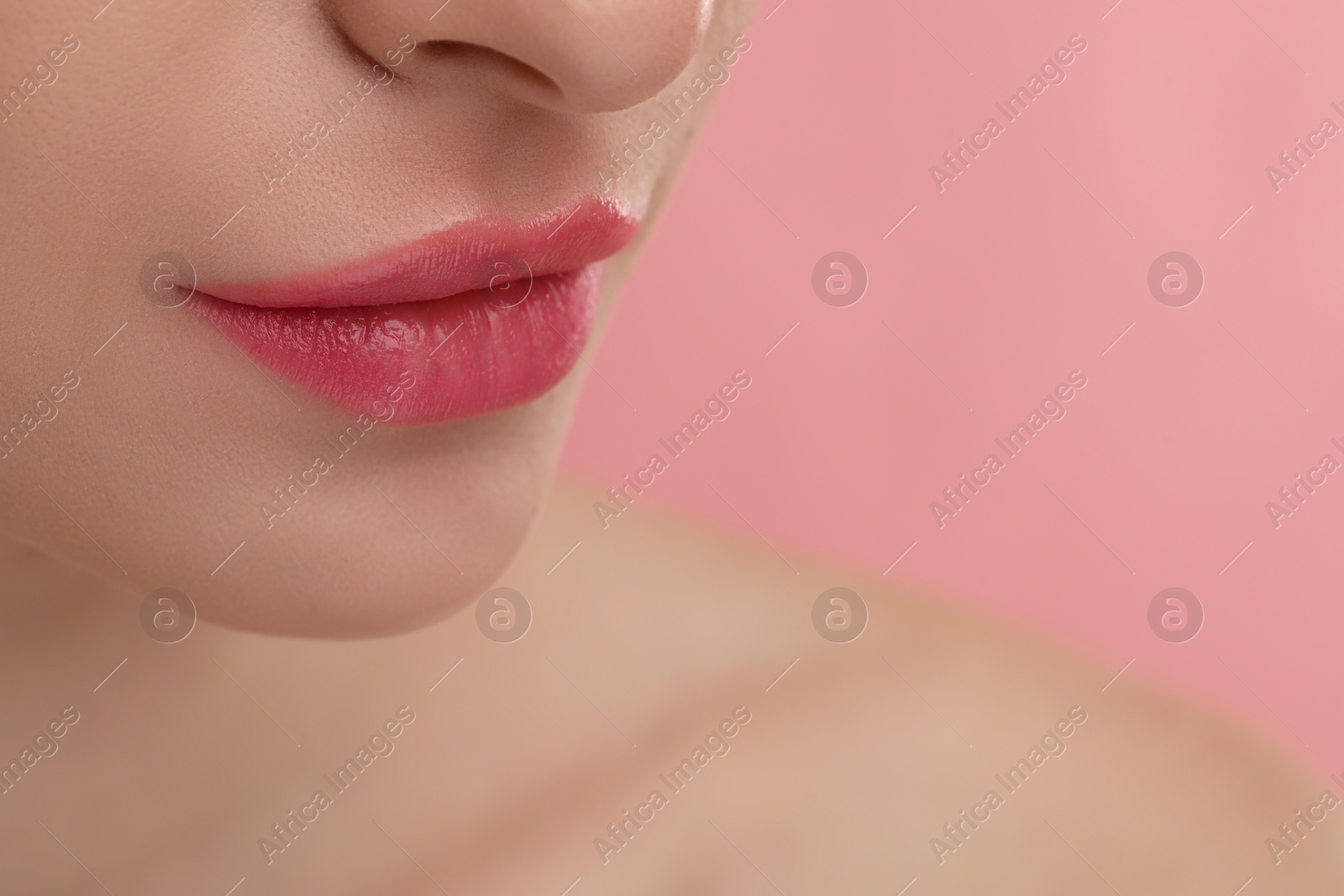 Photo of Young woman with beautiful full lips on pink background, closeup