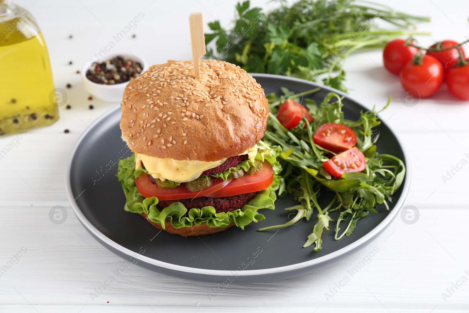 Photo of Delicious vegetarian burger served with salad on white wooden table