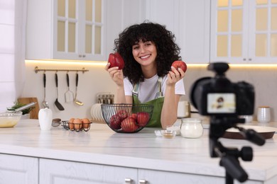 Photo of Smiling food blogger explaining something while recording video in kitchen