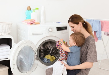 Photo of Housewife with little son doing laundry at home
