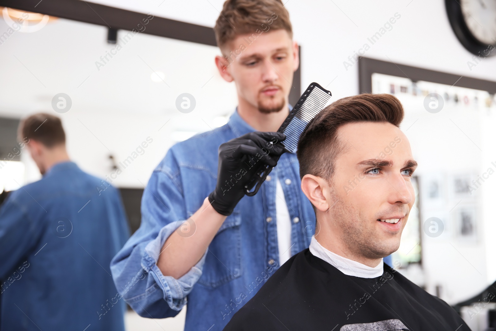 Photo of Professional barber working with client in hairdressing salon. Hipster fashion