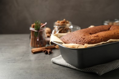Delicious gingerbread cake in baking dish on grey table, space for text