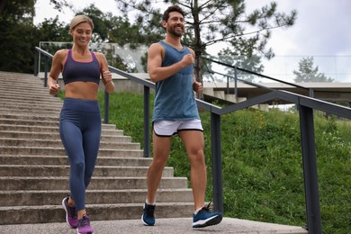 Photo of Healthy lifestyle. Happy couple running down stairs outdoors, low angle view