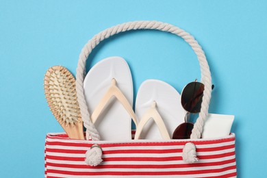 Photo of Flat lay composition with bag and other beach accessories on light blue background