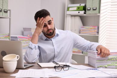 Overwhelmed man sitting at table in office