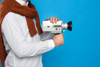 Photo of Man with vintage video camera on light blue background, closeup