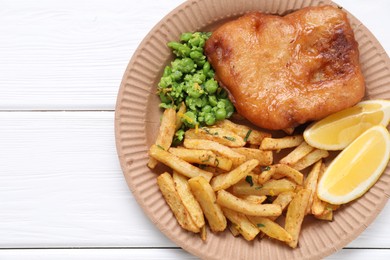 Photo of Tasty fish, chips, peas and lemon on white wooden table, top view. Space for text