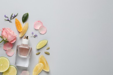 Photo of Flat lay composition with bottle of perfume and fresh citrus fruits on light grey background. Space for text