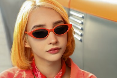 Photo of Beautiful young woman with bright dyed hair in sunglasses outdoors