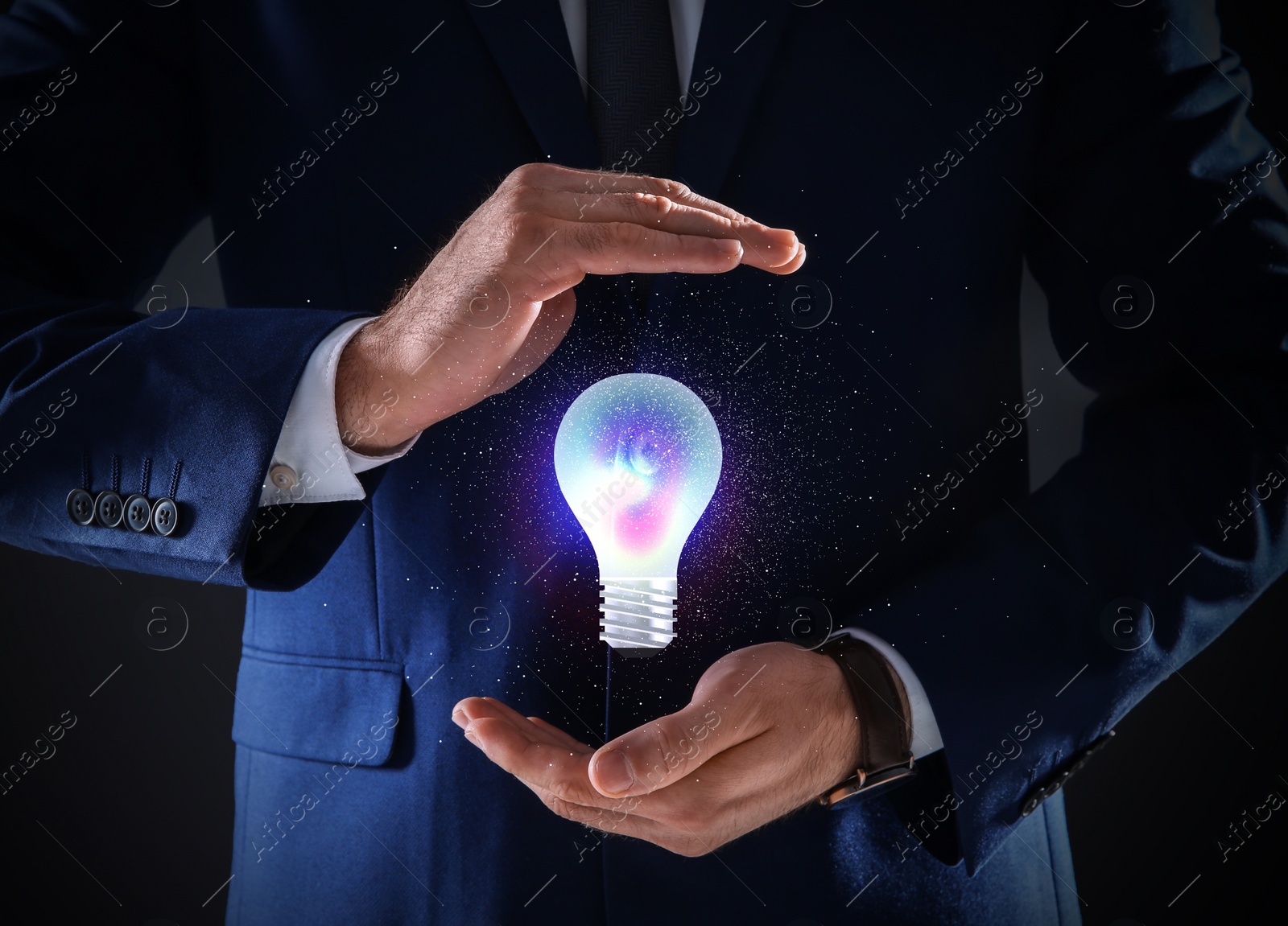 Image of Idea concept. Businessman demonstrating glowing light bulb illustration on dark background, closeup