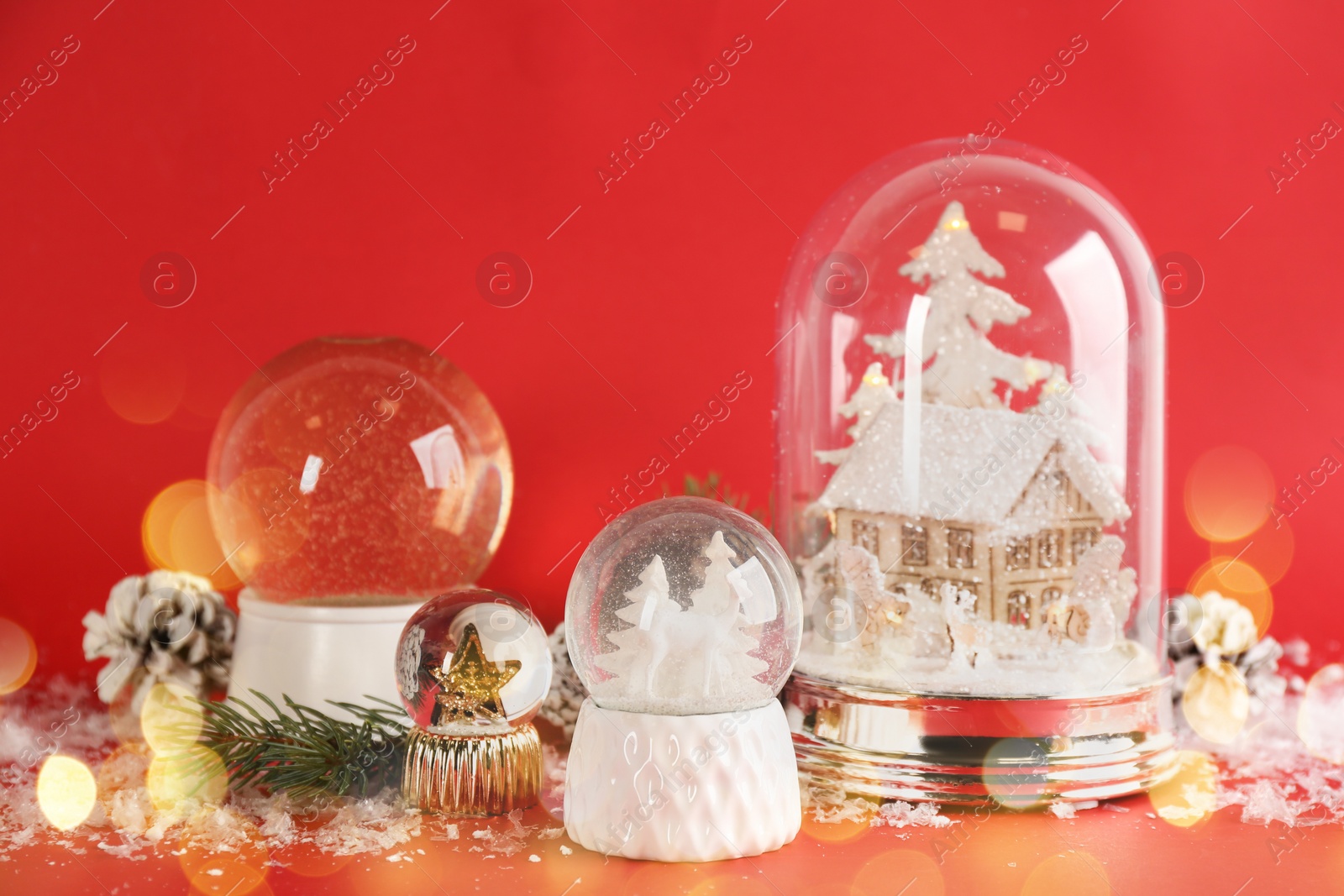 Image of Beautiful Christmas snow globes on red background, bokeh effect